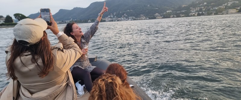 People on a boat enjoying a scenic lake view with mountains in the background.