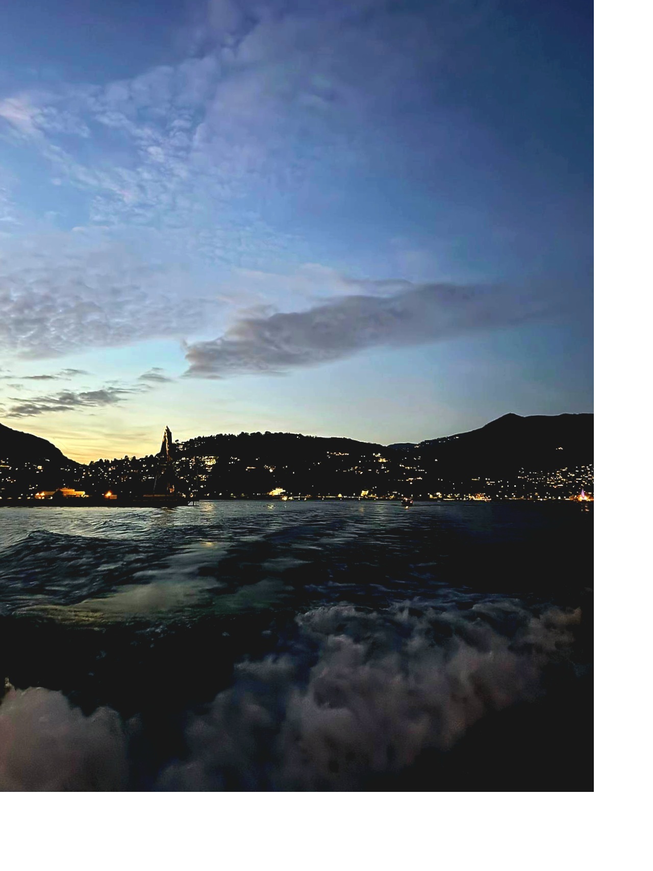 Lake Como sunset boat tour at dusk with city lights reflecting on the water