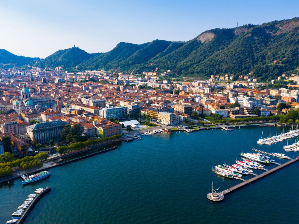 Aerial view of a coastal city with a marina, surrounded by hills.