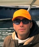 Person in an orange cap and sunglasses on a boat.